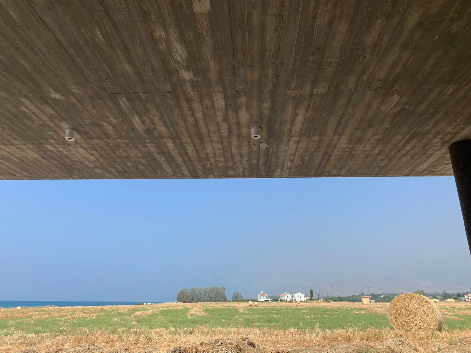 Contemporary Aris Residence in Polis Chrysochous with a deep board-formed concrete canopy framing sea views